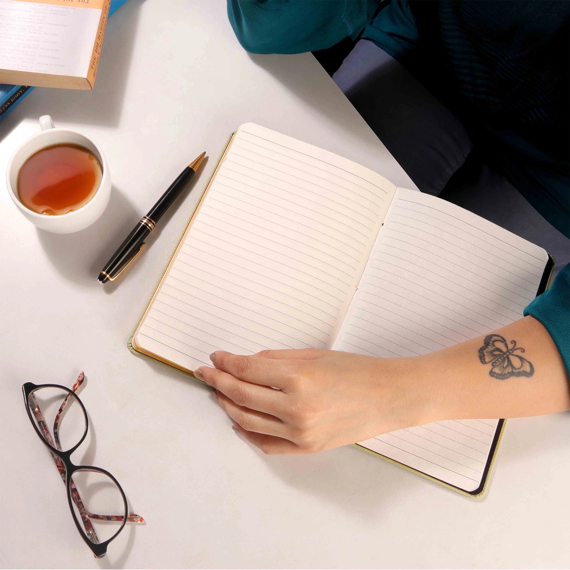 Open leather notebook on work desk with hand and accessories